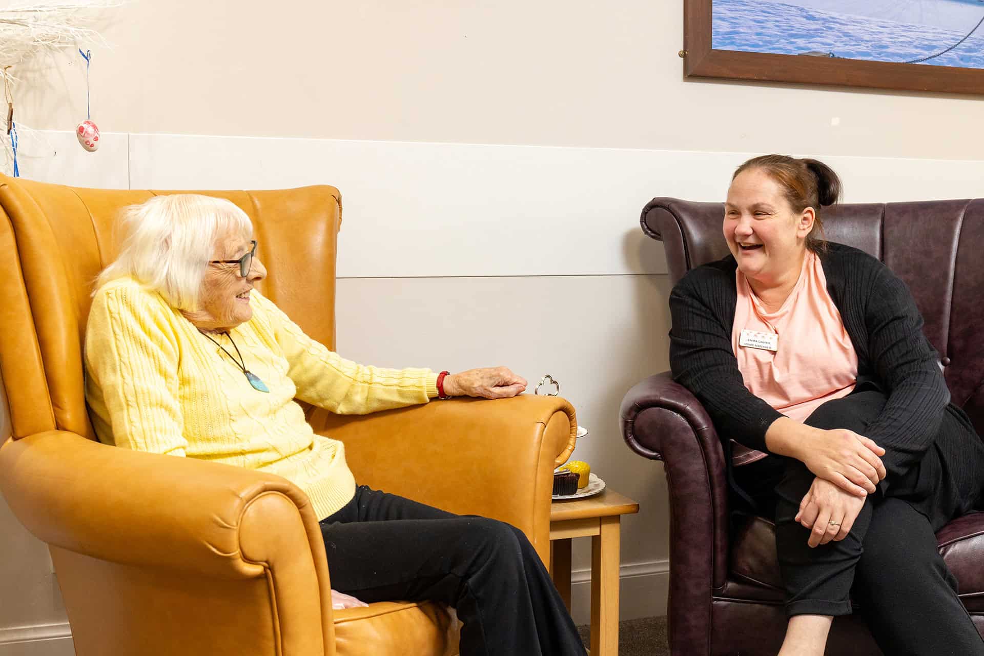 Care home staff engaging with elderly resident in a friendly conversation.