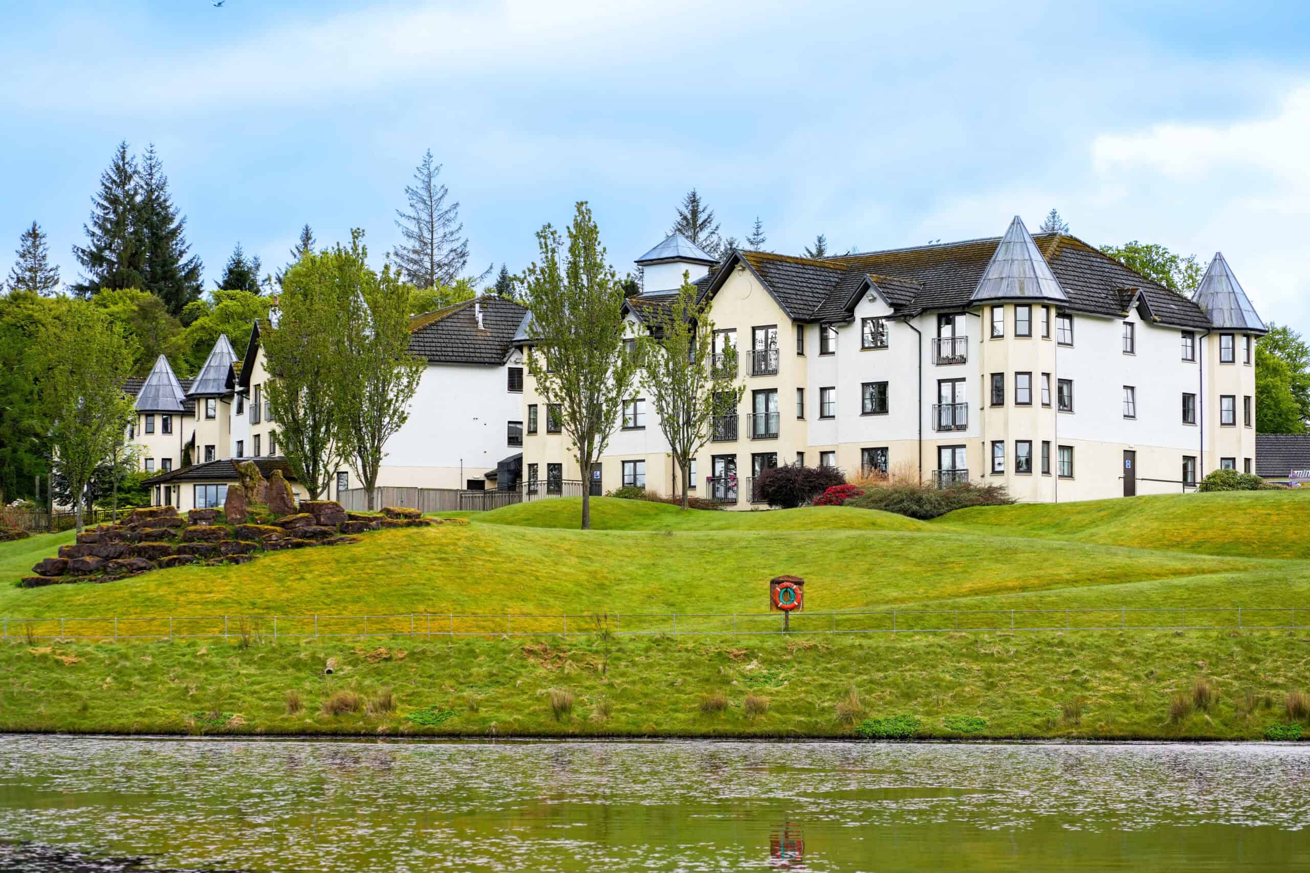 Elegant white apartment complex with turrets near a lake in Argyll, Scotland.